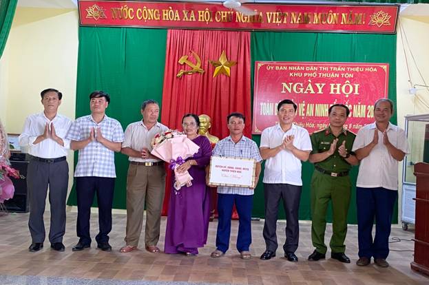 A group of people standing in front of a red and green banner

Description automatically generated